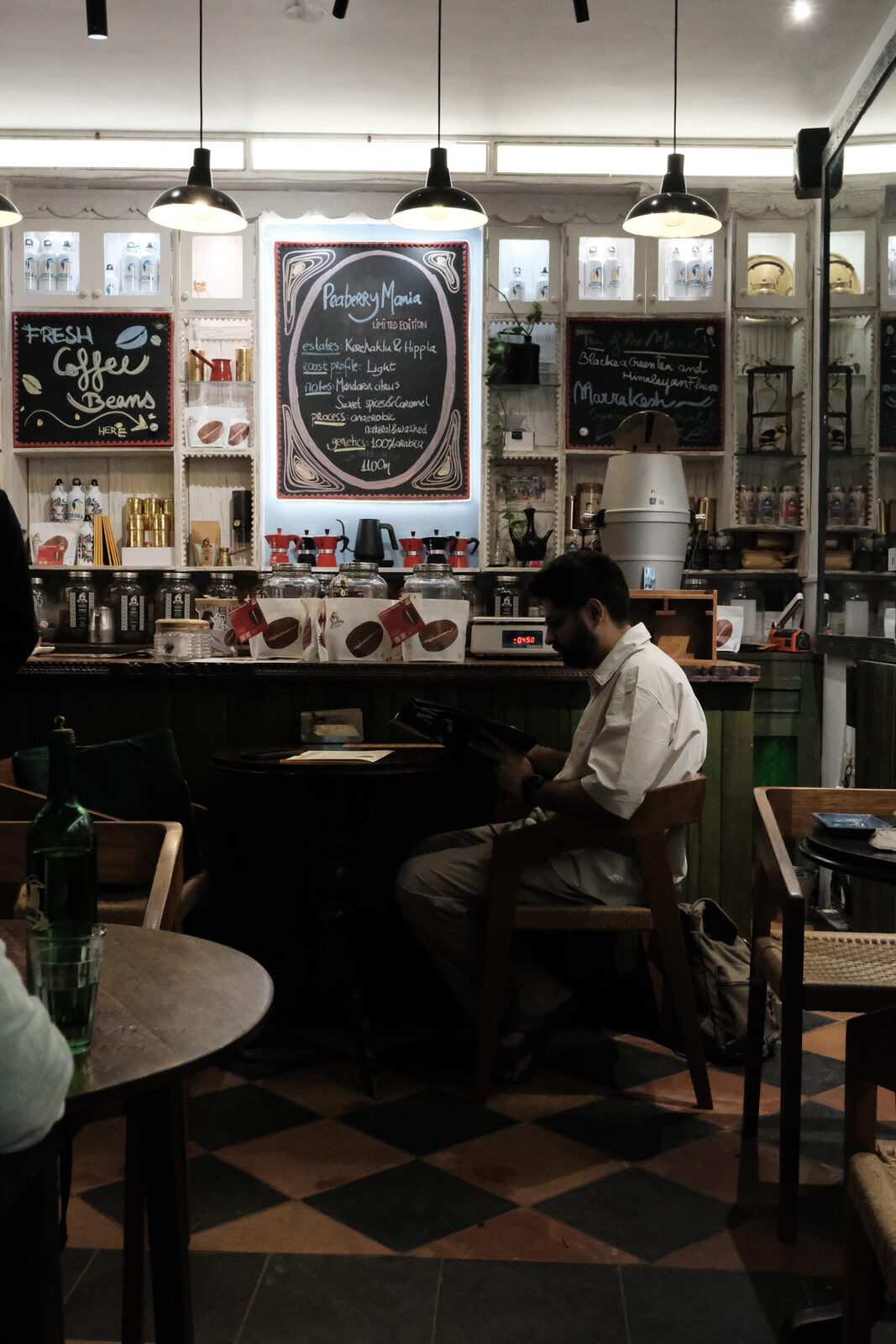 Interior of Marc's Coffees in Auroville with hand-drawn chalkboard menus and pendant lights over a green counter.